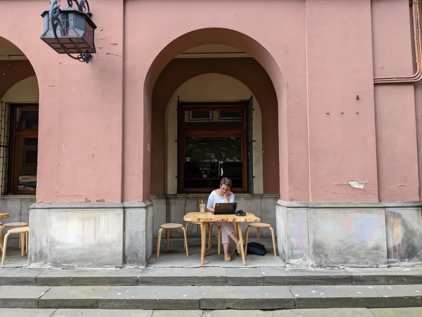 Woman working on a laptop outside a cafe in Warsaw, Poland. Relaxing, urban vibe.