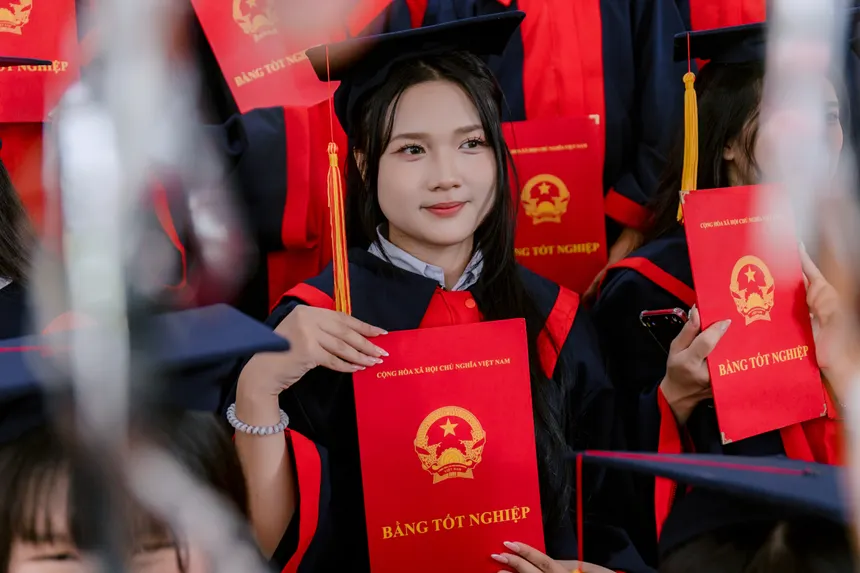 Group of students celebrating graduation with diplomas in hand, wearing caps and gowns.