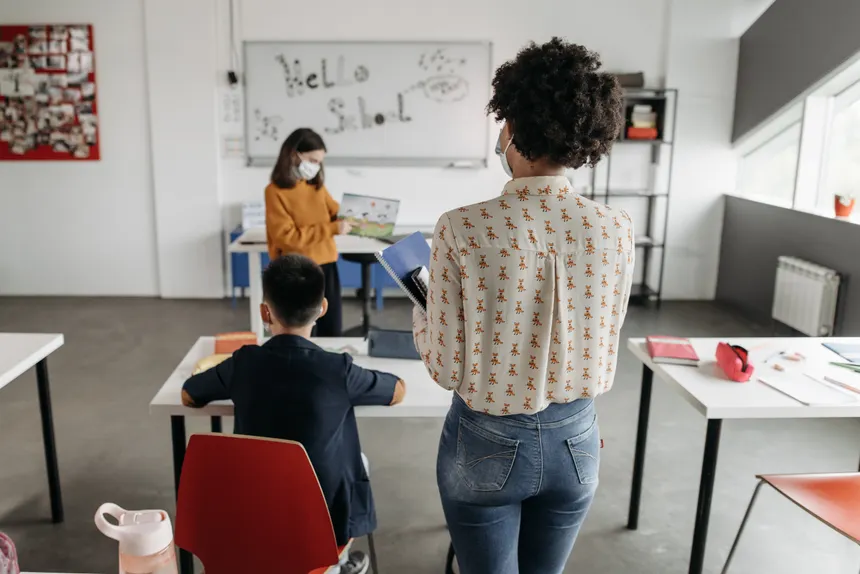 Teacher and students in a brightly lit classroom during a lesson.