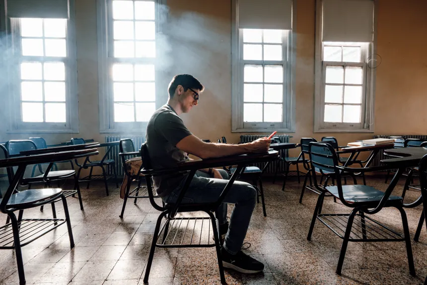 A student diligently studying alone in a sunlit university classroom in Buenos Aires, Argentina.