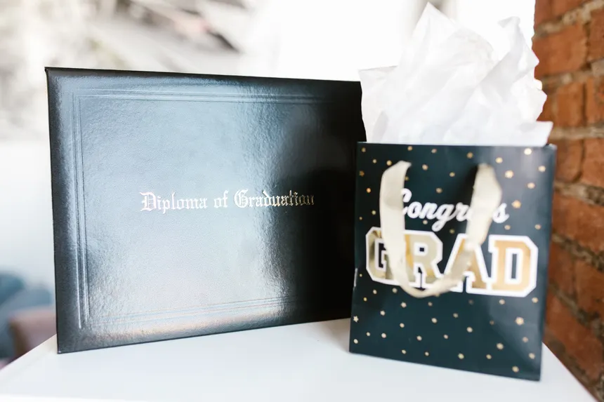 Diploma of graduation alongside a congratulatory gift bag, perfect for celebrating academic success.